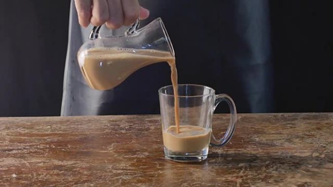 咖啡师将咖啡倒入玻璃杯中。