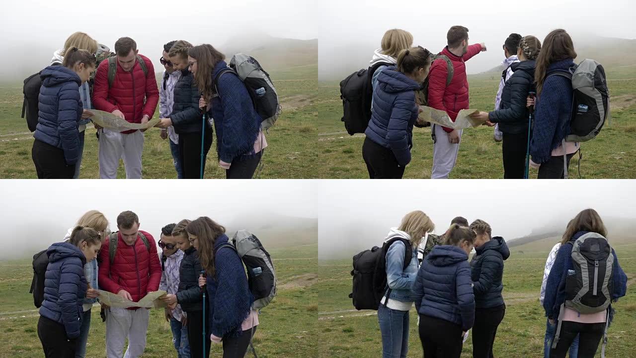 专业导游人员用背包向年轻游客解释路线阅读纸质地图并在山上带领路线