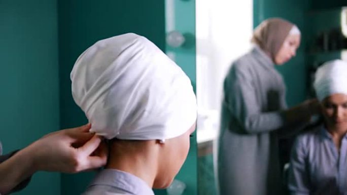 镜子附近的穆斯林妇女为迷人的新娘绑上伊斯兰头巾