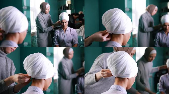 镜子附近的穆斯林妇女为迷人的新娘绑上伊斯兰头巾