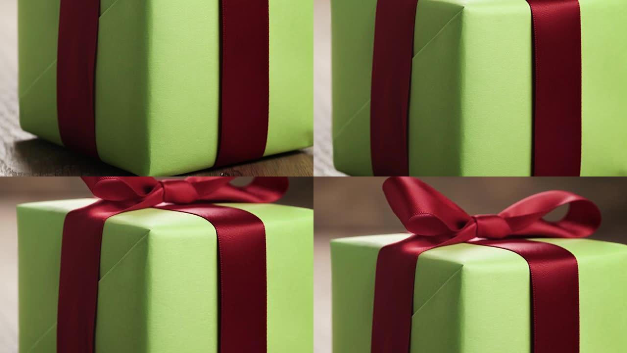 橡木桌上带红丝带蝴蝶结的简单绿纸礼品盒，带复印空间