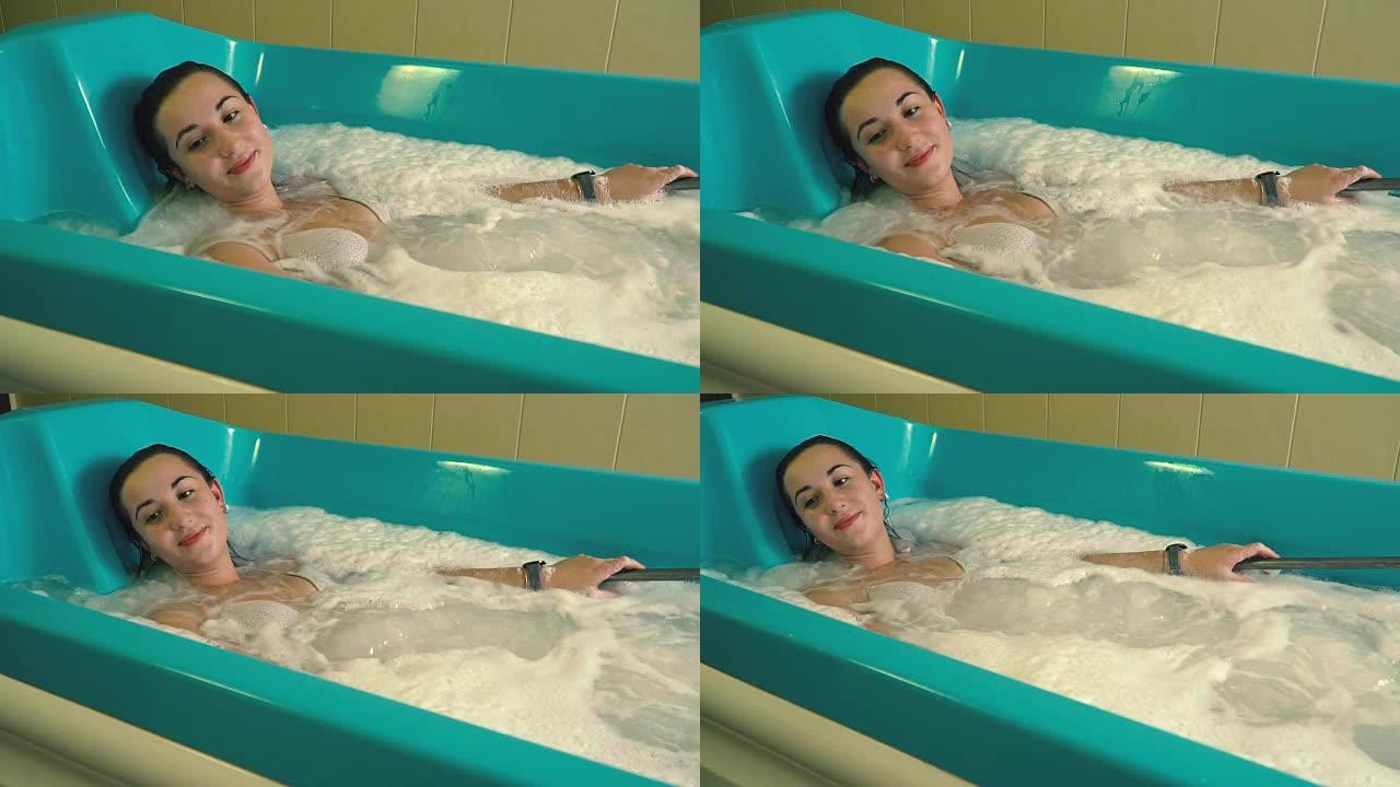 一个放松的女孩躺在泡沫浴中进行水力按摩，手上有一个防水时钟，慢动作