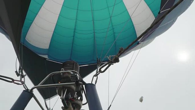 热气球。燃烧器将火焰引导到天空中背景氦飞艇上的信封中