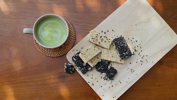 绿茶随时可以喝，与谷物，烤白芝麻和芝麻放在木盘子上，为需要保健的人提供食物。
