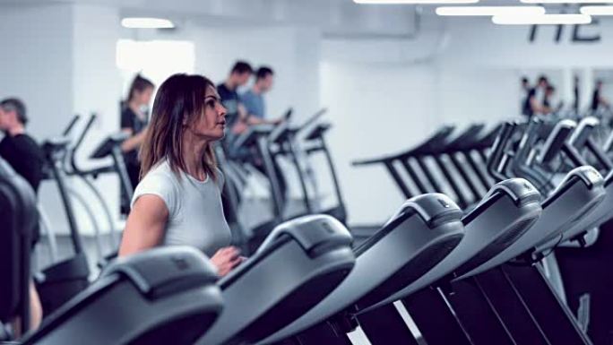 Adult woman runs on treadmill at the fitness centr