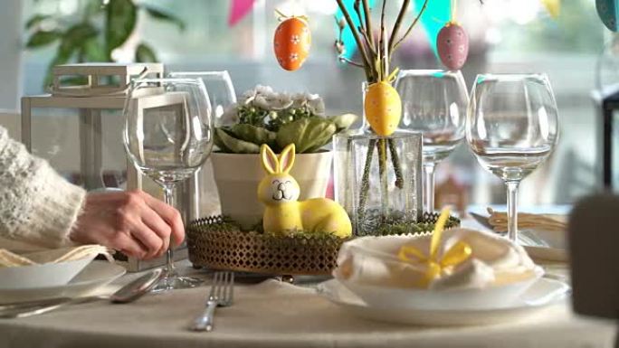 年轻女子用兔子和鸡蛋装饰摆放复活节节日餐桌