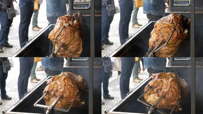 在明火上方的烤架上准备的大块肉烤猪腿。捷克共和国布拉格的街头美食