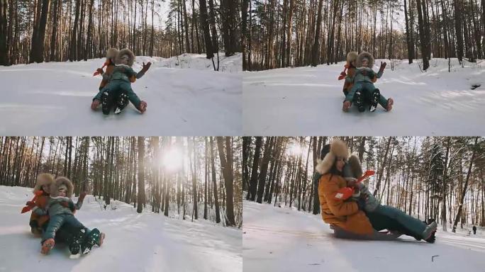 年轻的母亲和小女儿在slomo的冬季公园的雪橇上玩得开心