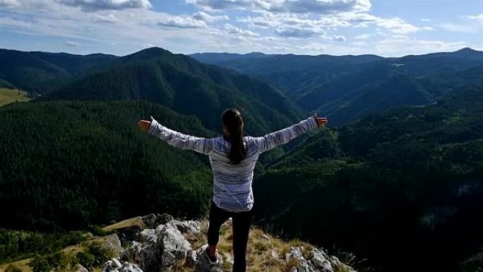 女人举起手臂在山顶看日落的观点徒步女孩举起手臂庆祝生活风景自然景观享受假期旅行冒险