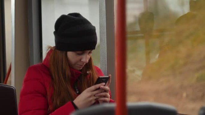 悲伤的年轻女子在晚上乘公共汽车时用手机打字。公交车车窗内散焦的城市交通慢动作4k镜头