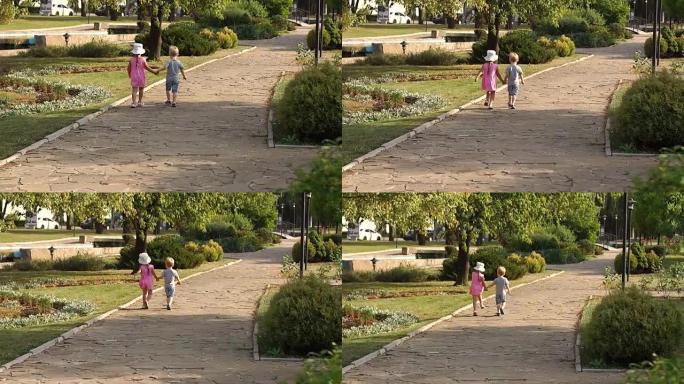 两个可爱的孩子在夏季公园的小巷里散步。