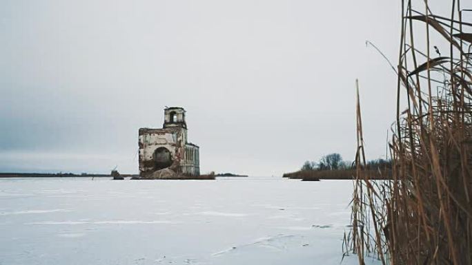 被雪覆盖的冰冻湖中间的废弃教堂建筑