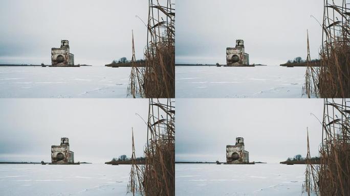 被雪覆盖的冰冻湖中间的废弃教堂建筑