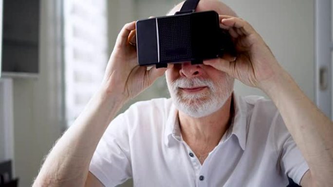 好看的帅气白衣高级男子在家摘下VR 360眼镜。活跃的老年人