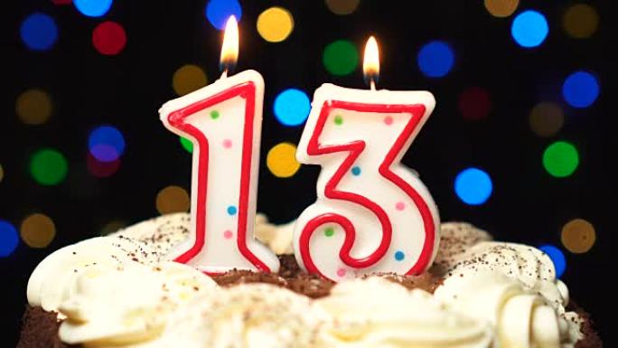 蛋糕上的第13号-十三岁生日蜡烛燃烧-最后吹灭。彩色模糊背景