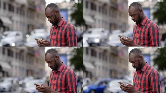 英俊的年轻黑人在街上使用智能手机