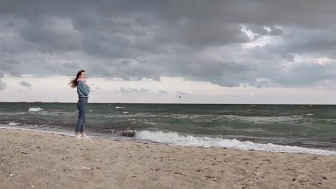 年轻漂亮的女孩蓝精灵在汹涌的海洋岸边飞行的海鸥上