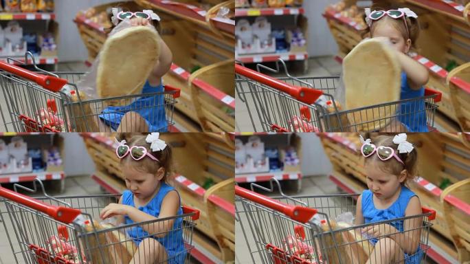 小女孩坐在超市的手推车里吃东西，拿着面包。婴儿购物