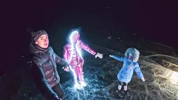 家人在滑冰之夜，自拍。母亲，父亲，女儿和儿子一起在裂缝中的冰上骑行。运动员的户外冬季乐趣冬季天气晴朗
