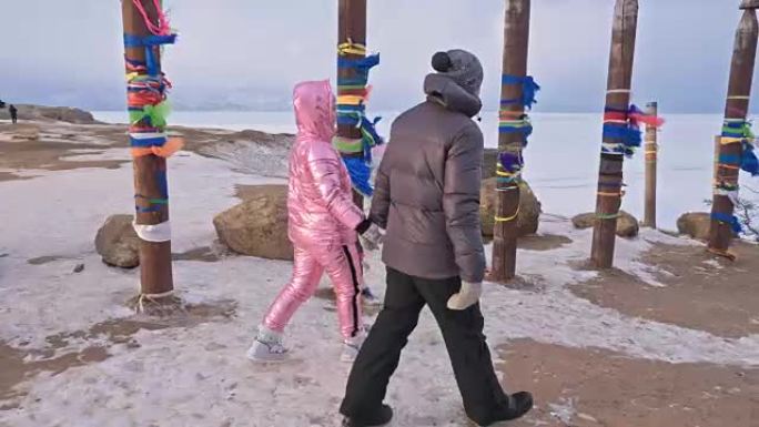 年轻夫妇喜欢在冬季山顶的户外散步。冬天在贝加尔湖圣地用彩带的佛教仪式杆。