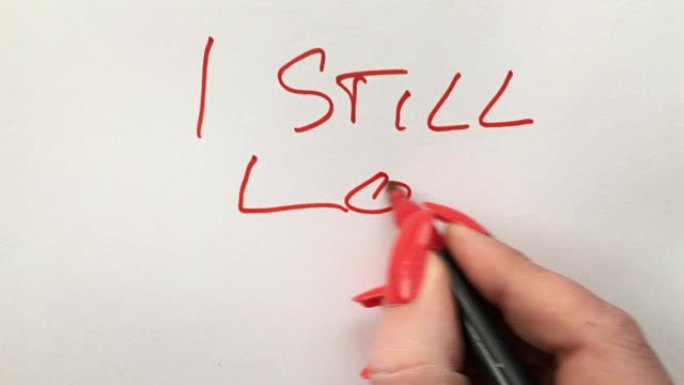 女人用白纸上的红色毡尖笔写着我仍然爱你