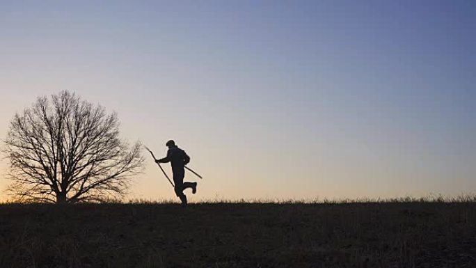 一个满意的农民在田野里跳舞。野外日落或日出的轮廓。慢动作