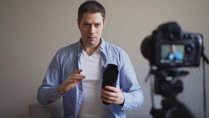 英俊的男人制作关于相机镜头的视频博客。
