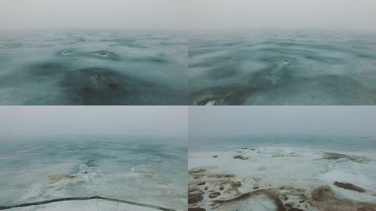 在雾蒙蒙的寒冷冬季，在冰冻的海上海岸线上飞行，冰裂