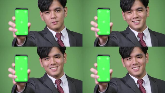 年轻英俊的亚洲商人展示手机