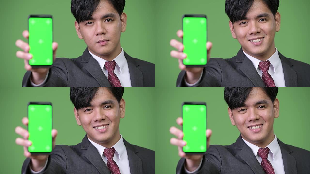年轻英俊的亚洲商人展示手机