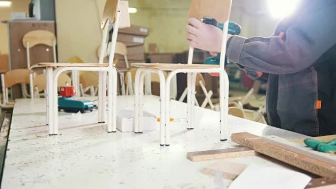 工人木匠正在家具厂用电动螺丝刀拧椅子腿