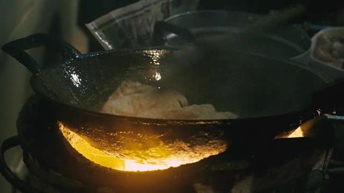在泰国老式火炉上用金属鳍状肢和飞盘烹饪曼谷街头食品。