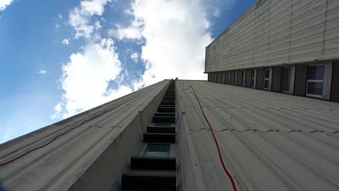 无所畏惧的业余运动员在摩天大楼墙上用绳索下降。