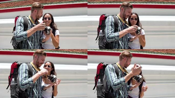 泰国度假期间，情侣游客在相机中看着照片