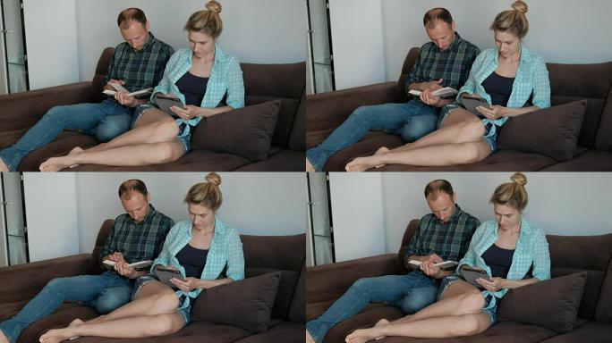 在沙发上，一个男人坐着一本书，一个女人坐着平板电脑
