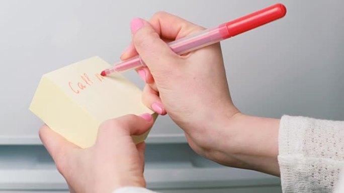 特写女人的手在黄色贴纸纸上写着 “呼唤我” 和 “画一颗心”。