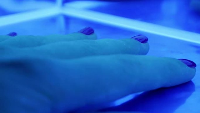 在美容院用女性手固定凝胶指甲油的紫外线led灯的特写镜头