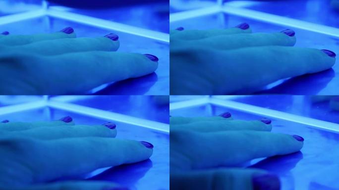 在美容院用女性手固定凝胶指甲油的紫外线led灯的特写镜头