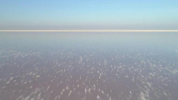 低角度无人机快速飞向白色盐湖上方，并带有盐沉积物。鸟瞰图。