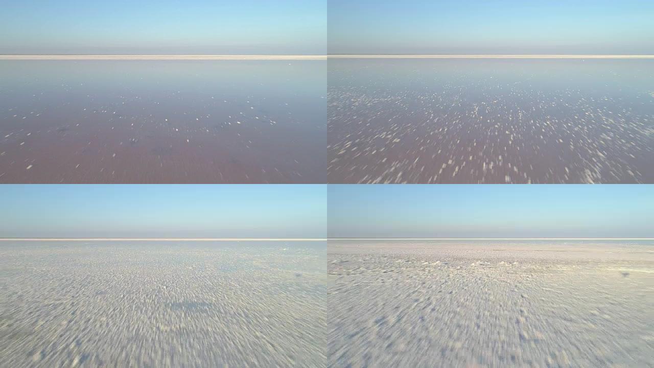 低角度无人机快速飞向白色盐湖上方，并带有盐沉积物。鸟瞰图。