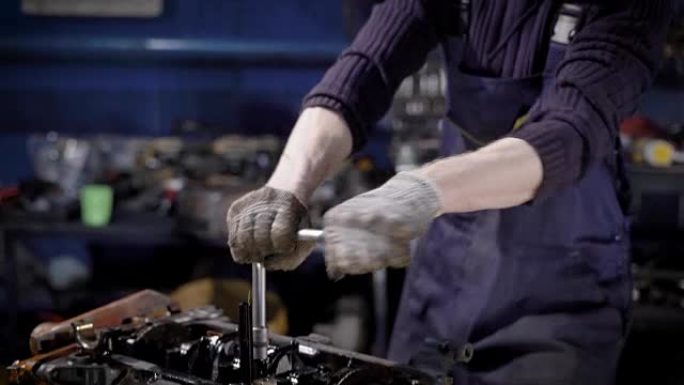 一位年轻的机械师在车库里用汽车发动机工作的特写镜头
