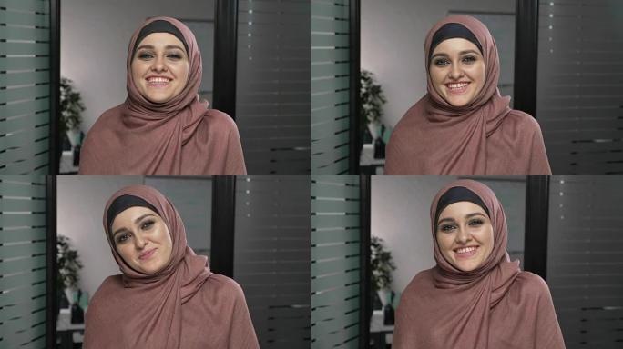 穿着粉红色头巾的年轻快乐阿拉伯女孩笑了。看着相机，肖像。60 fps