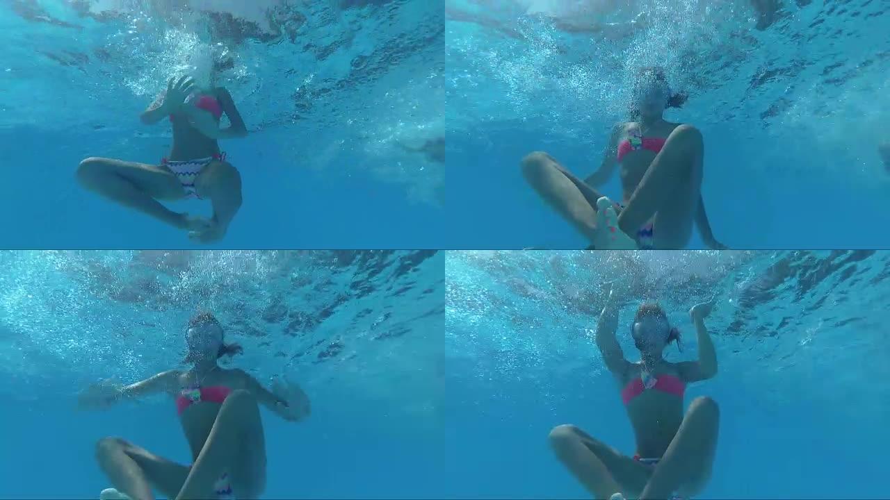 戴着面具的女孩在游泳池里潜水看着镜头