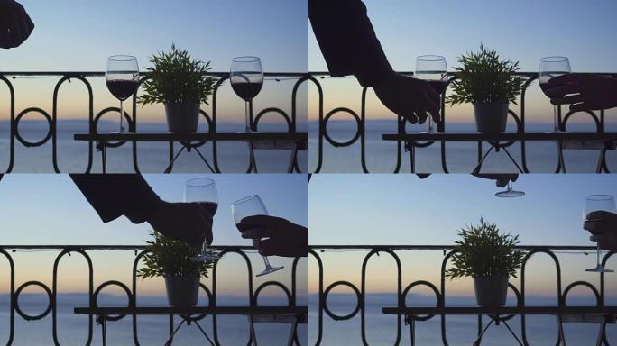 一男一女坐在阳台上，在大海的背景上喝着红酒。特写。