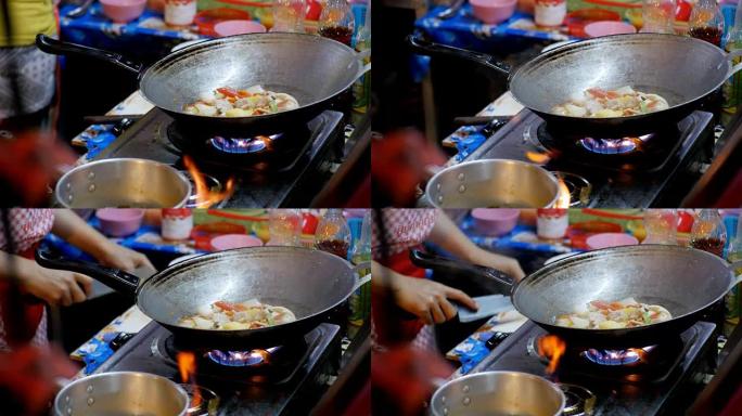 女摊贩在Jomtien夜市的煎锅中准备亚洲食物。泰国，芭堤雅