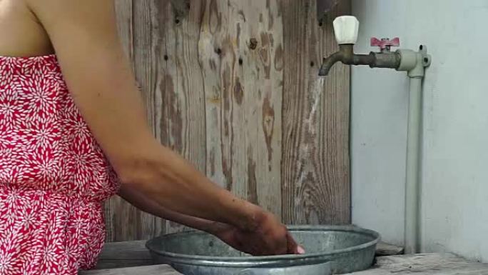 年轻女孩在乡村的水槽里洗手