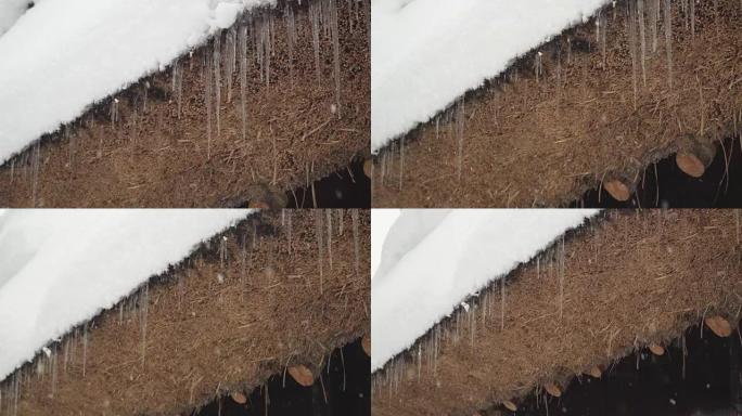 低角度平移: 雪下的Shirakawago村房屋屋顶上的冰冻长矛