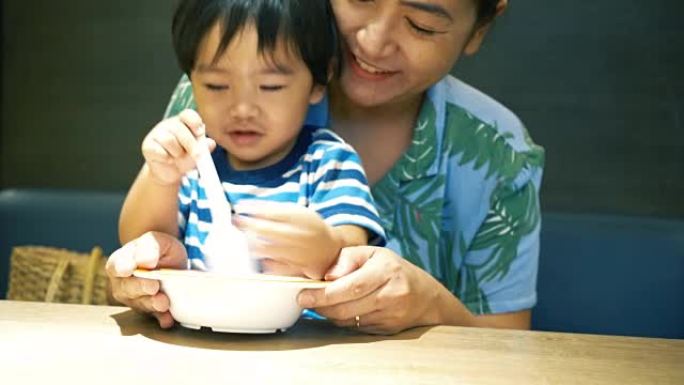 亚洲男婴与妈妈一起吃饭和玩耍