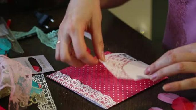 这个女孩在家从事制作贺卡的工作。采用纸、花边、编织物等材料。