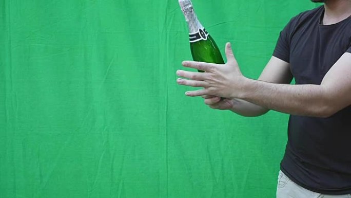 绿色背景下，一个男人的手拿着一瓶香槟